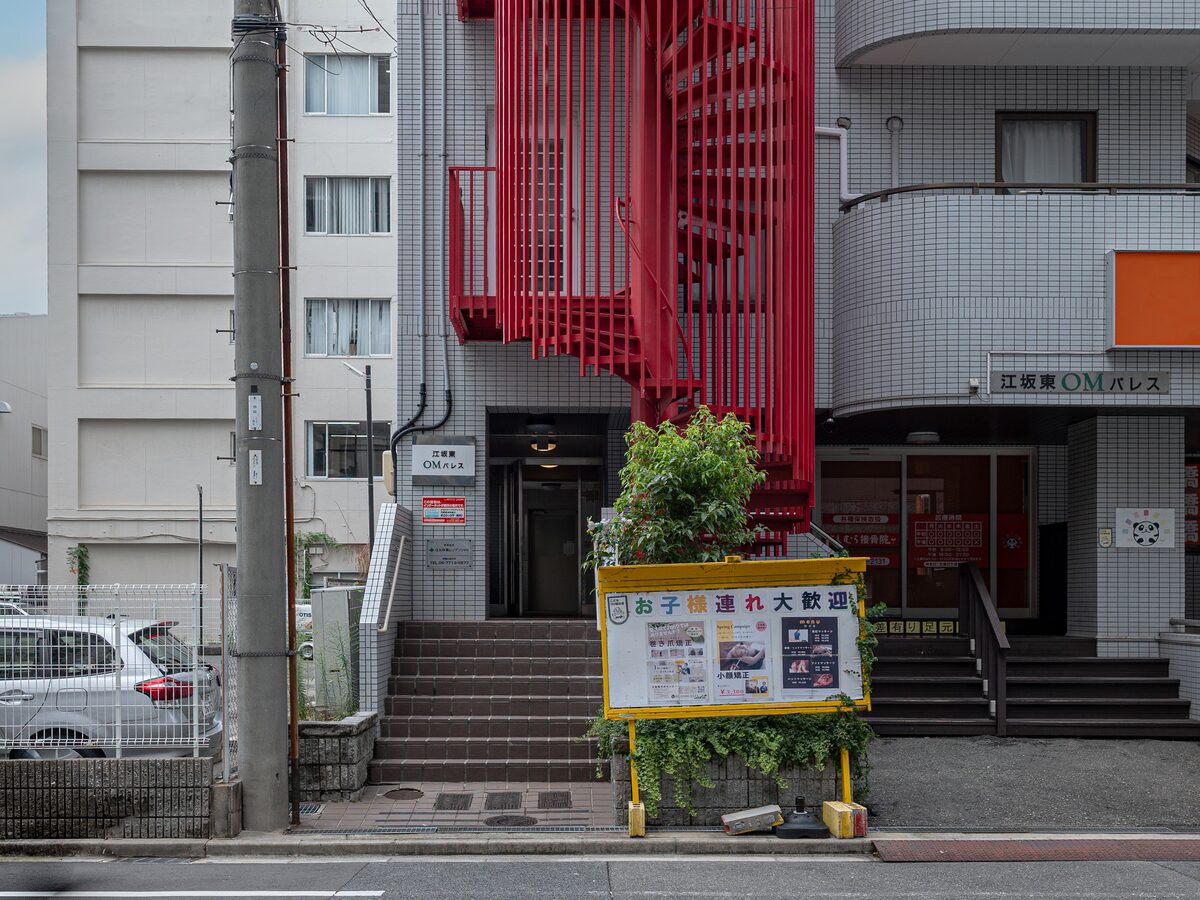 Outside of Esaka Higashi OM Palace. Look for the red spiral staircase. The building name sign is on the right, and the entrance is up the steps in the middle.