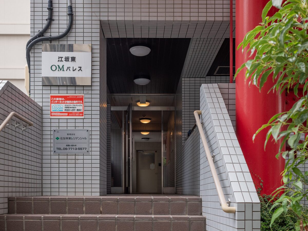 Entrance of Esaka Higashi OM Palace. The building name plate is on the wall to the left. Go up a few steps to enter.
