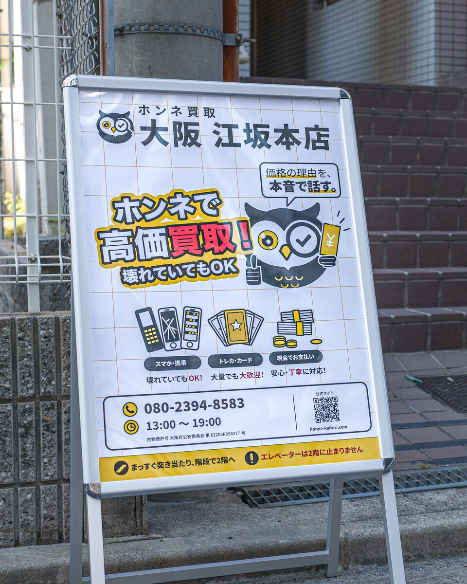 ビル入口の階段の前に置いた「ホンネ買取 大阪 江坂本店」の立て看板