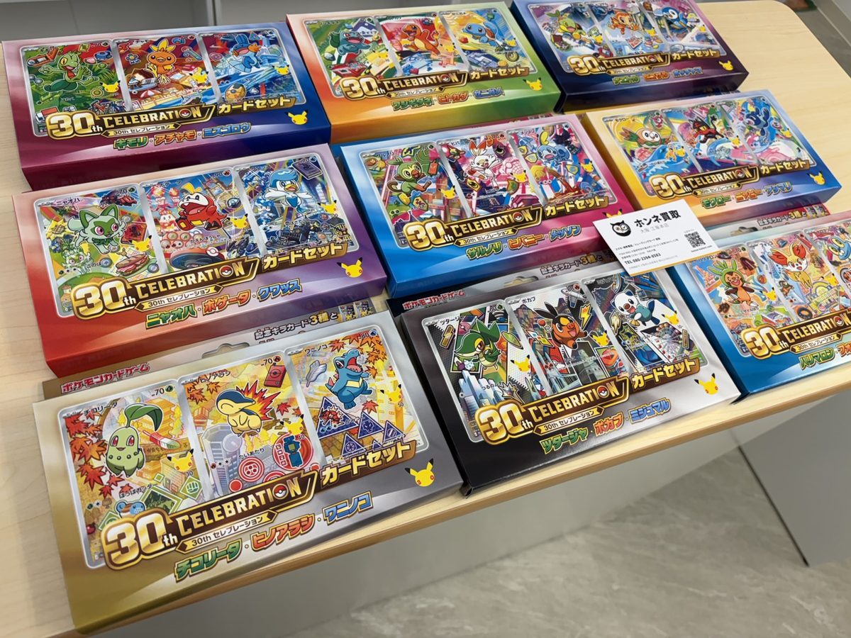 テーブルに並べたポケモンカード「30th CELEBRATION」のカードセット9種類とホンネ買取の名刺